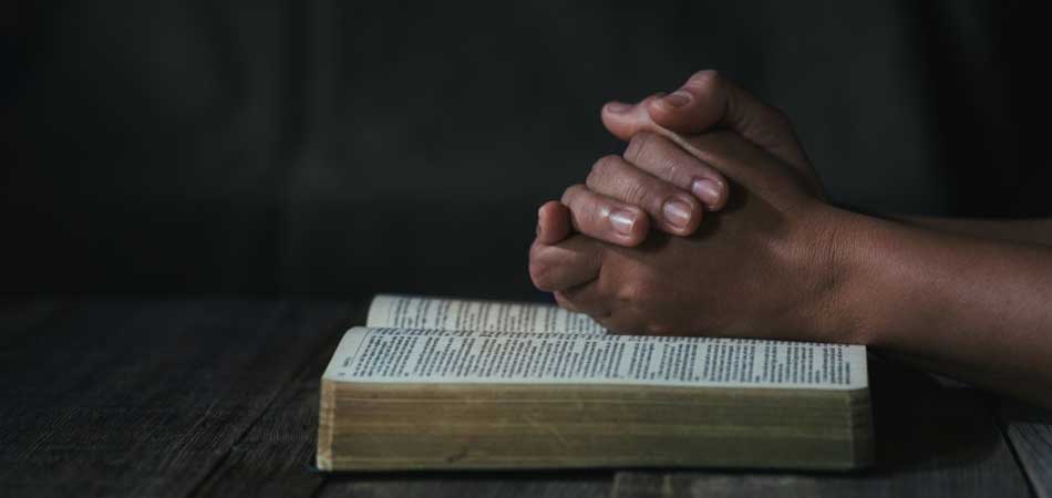 Hands Praying On Bible